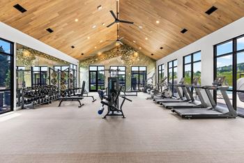 A spacious gym with treadmills, weights, and a ceiling fan.